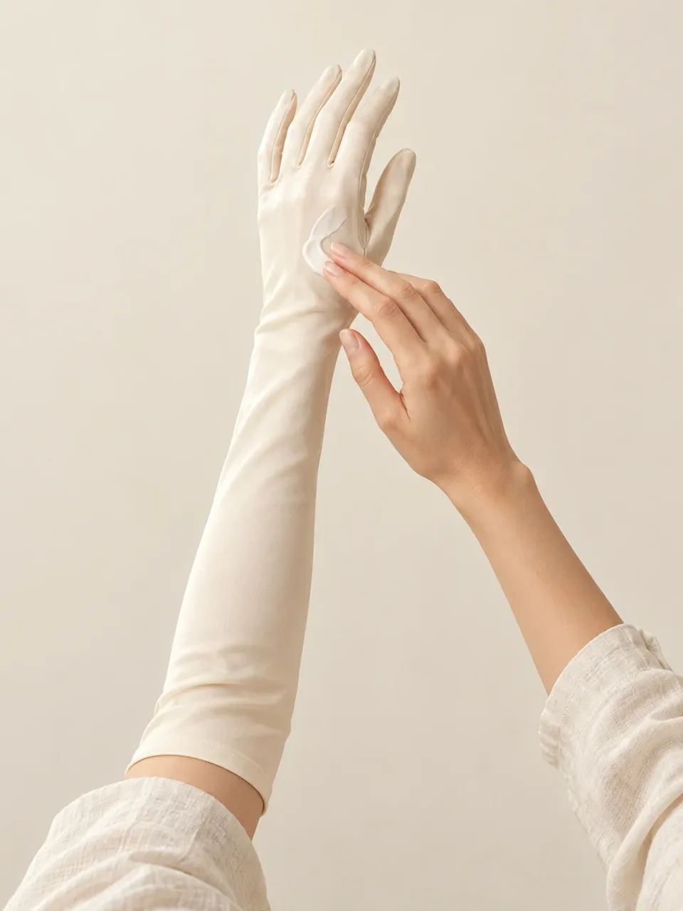 An arm in an ivory silk sleep glove as hand cream is smoothed on